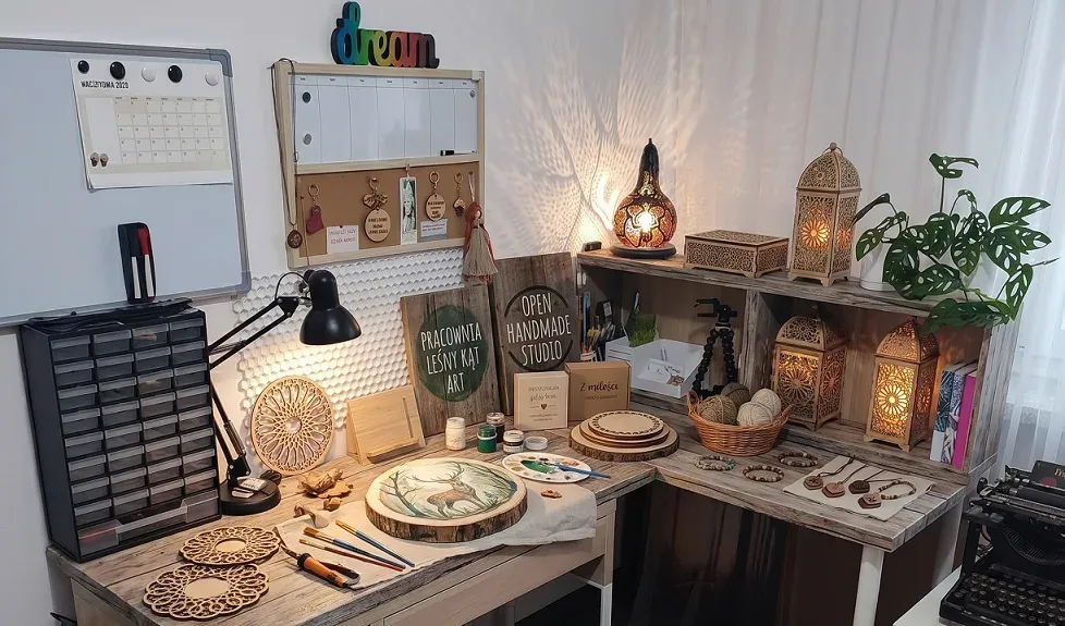 Pracownia rękodzielnicza: biurko z drewnianymi produktami, obrazami i szkatułkami ze sklejki